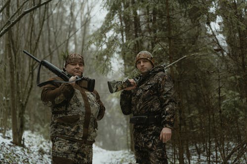 Two Men Standing on Forest Holding Rifles