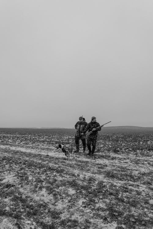 Two Men Standing in a Field with a Dog