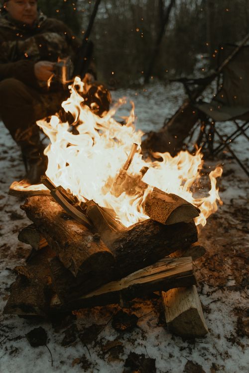 Free Warm campfire burning amidst winter snow, offering a cozy outdoor retreat. Stock Photo