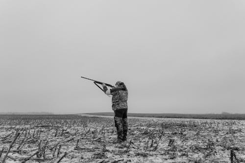 Monochrome Photo of a Man Aiming His Firearm