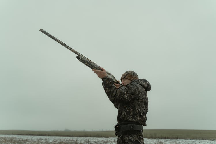 Man In Camouflage Uniform Aiming A Rifle