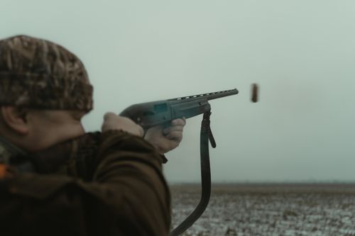 Free Adult male aiming a shotgun in a rural setting with camouflage clothing. Stock Photo