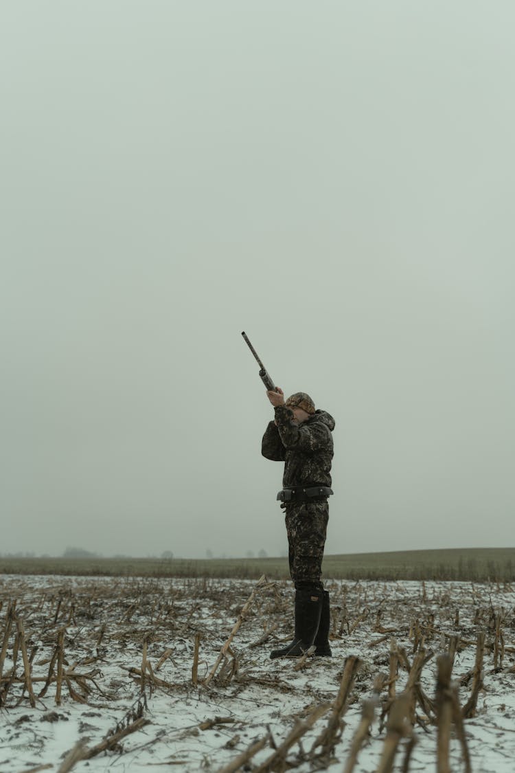 Photo Of A Hunter In Camouflage Clothes Aiming His Gun