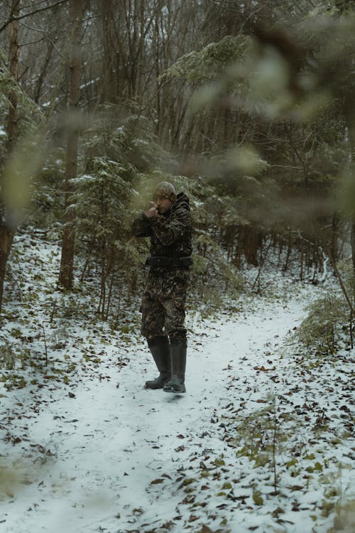 Photo of a Hunter Aiming His Gun Near Trees