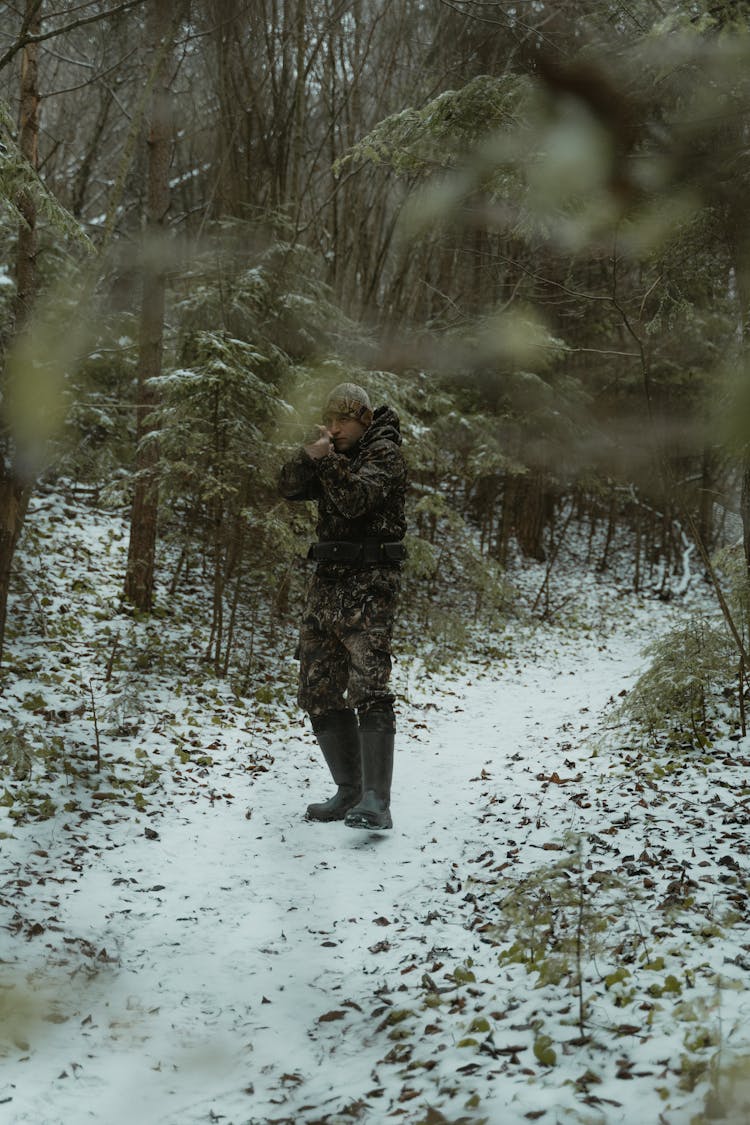 Photo Of A Hunter Aiming His Gun Near Trees