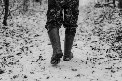 Black and White Photograph of a Person with Boots Walking on Snow