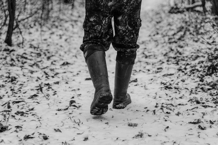 Black And White Photograph Of A Person With Boots Walking On Snow