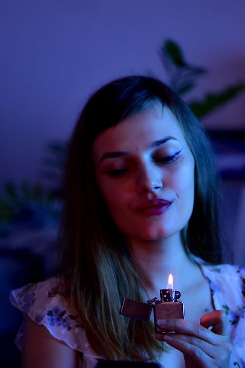 Peaceful woman with burning lighter in dark room