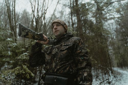 Free Man in camouflage with shotgun on a winter forest hunt, low angle view. Stock Photo