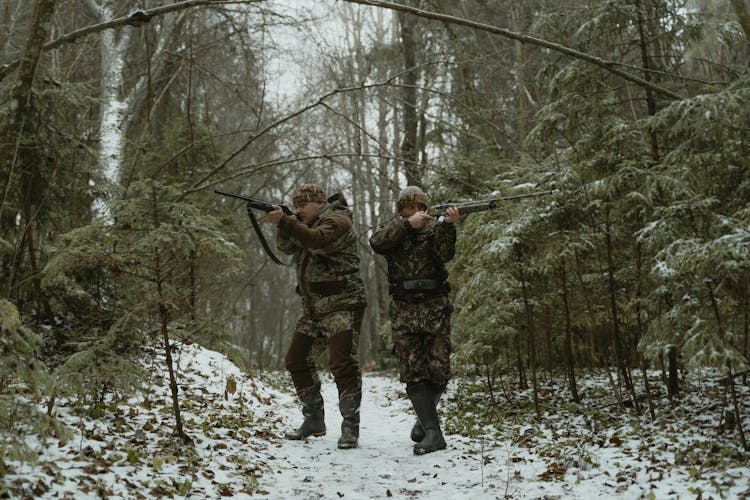 Hunters Aiming Their Rifles While In The Forest