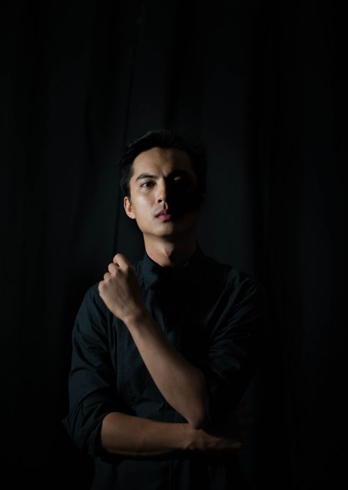 Free Minimalist portrait of a man in a black shirt against a dark background, emphasizing elegant simplicity. Stock Photo