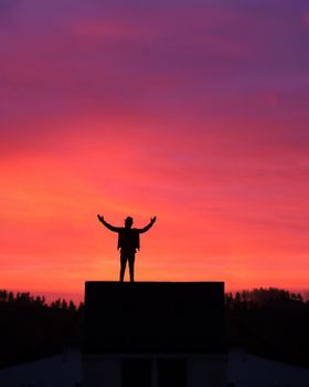 A silhouette of a person standing with arms raised against a vibrant sunset sky, creating a dramatic scene.. pexels, silhouet