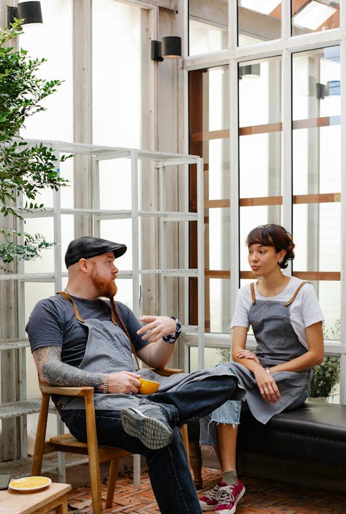 Couple of colleagues having conversation in aprons in terrace