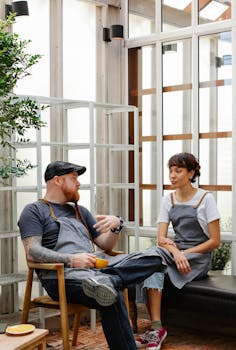 Coworkers enjoying a casual coffee break in a modern, indoor workspace with natural light.