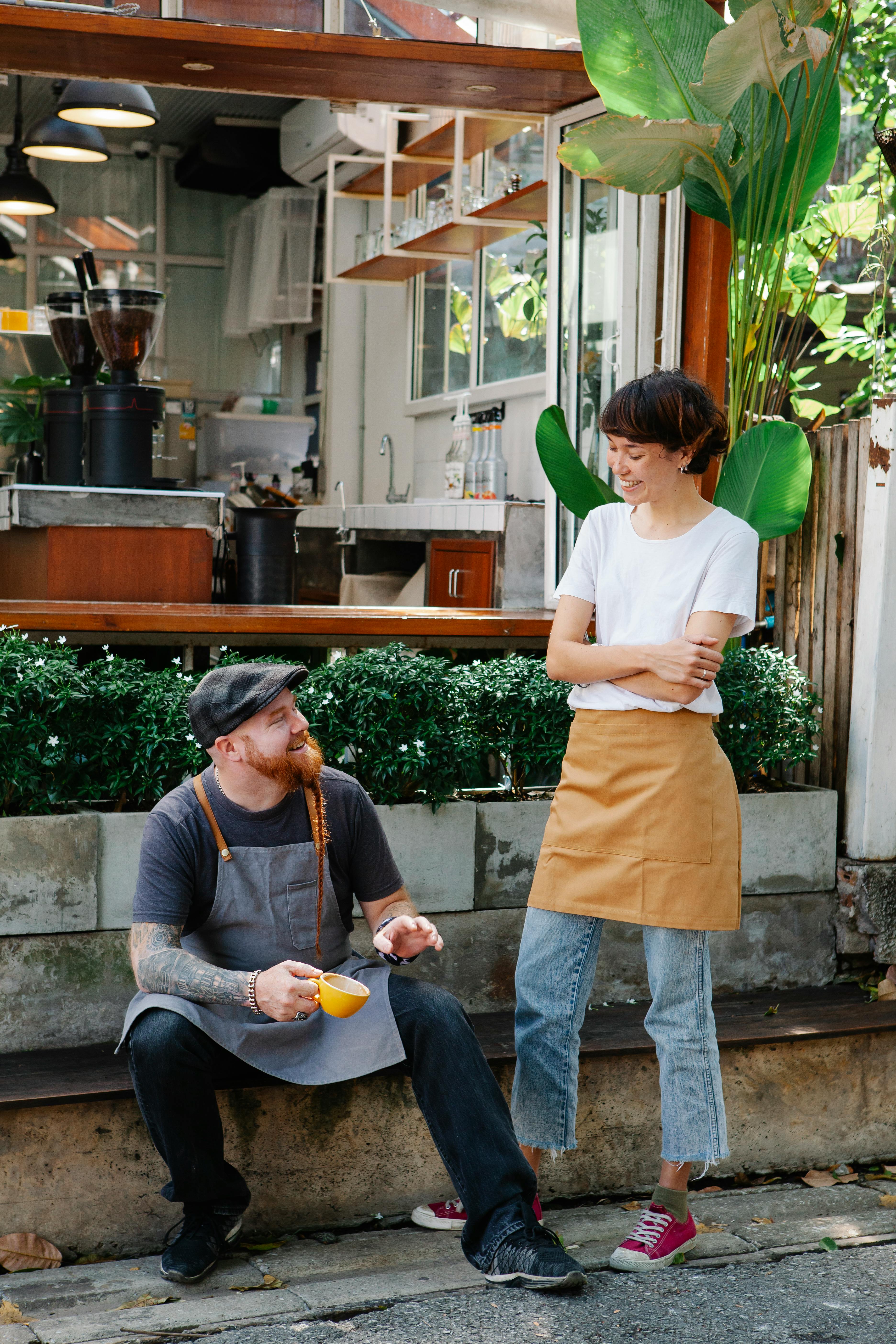 couple of coworkers speaking near cafe in street