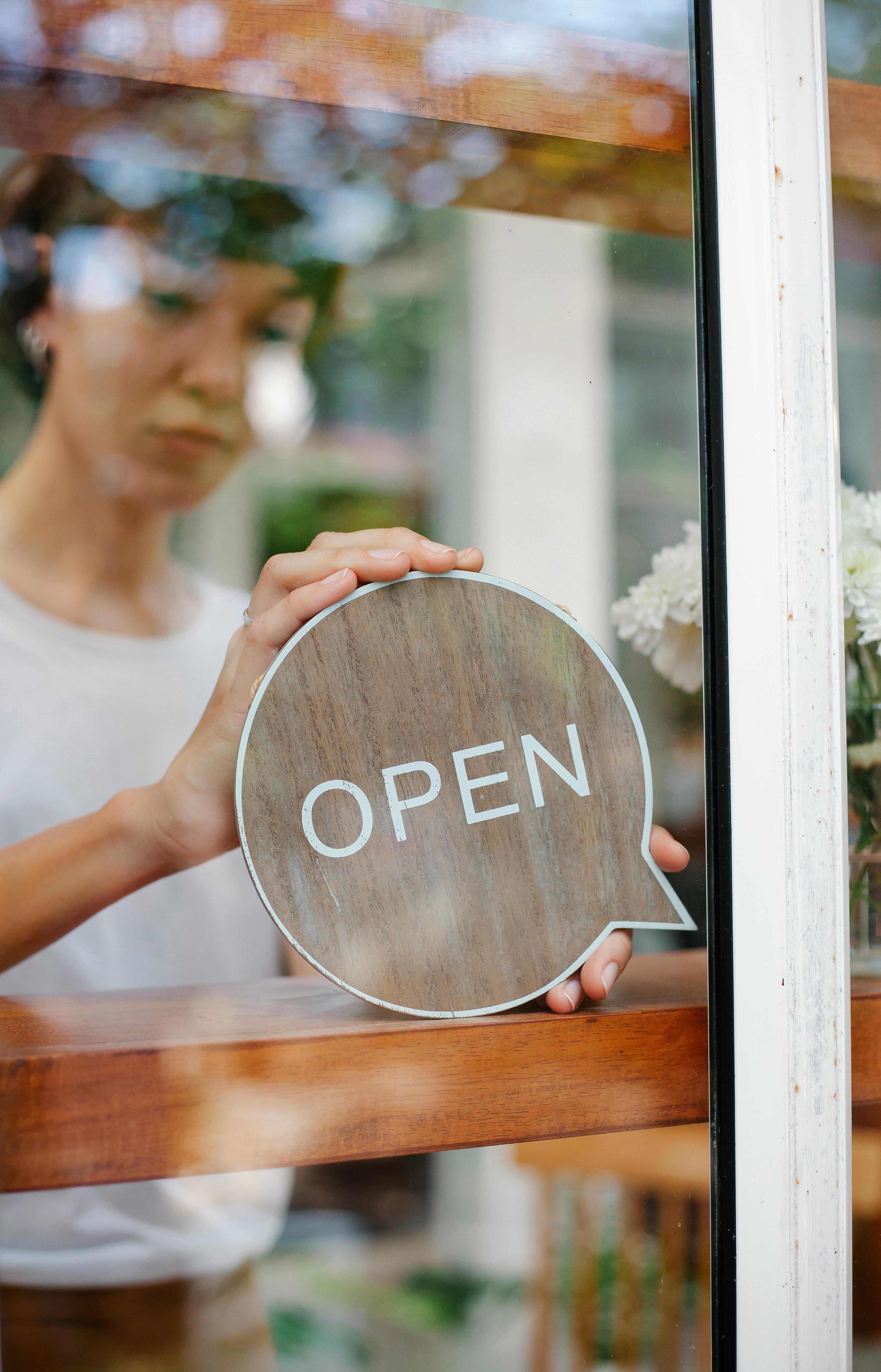 woman with sign open in cafe