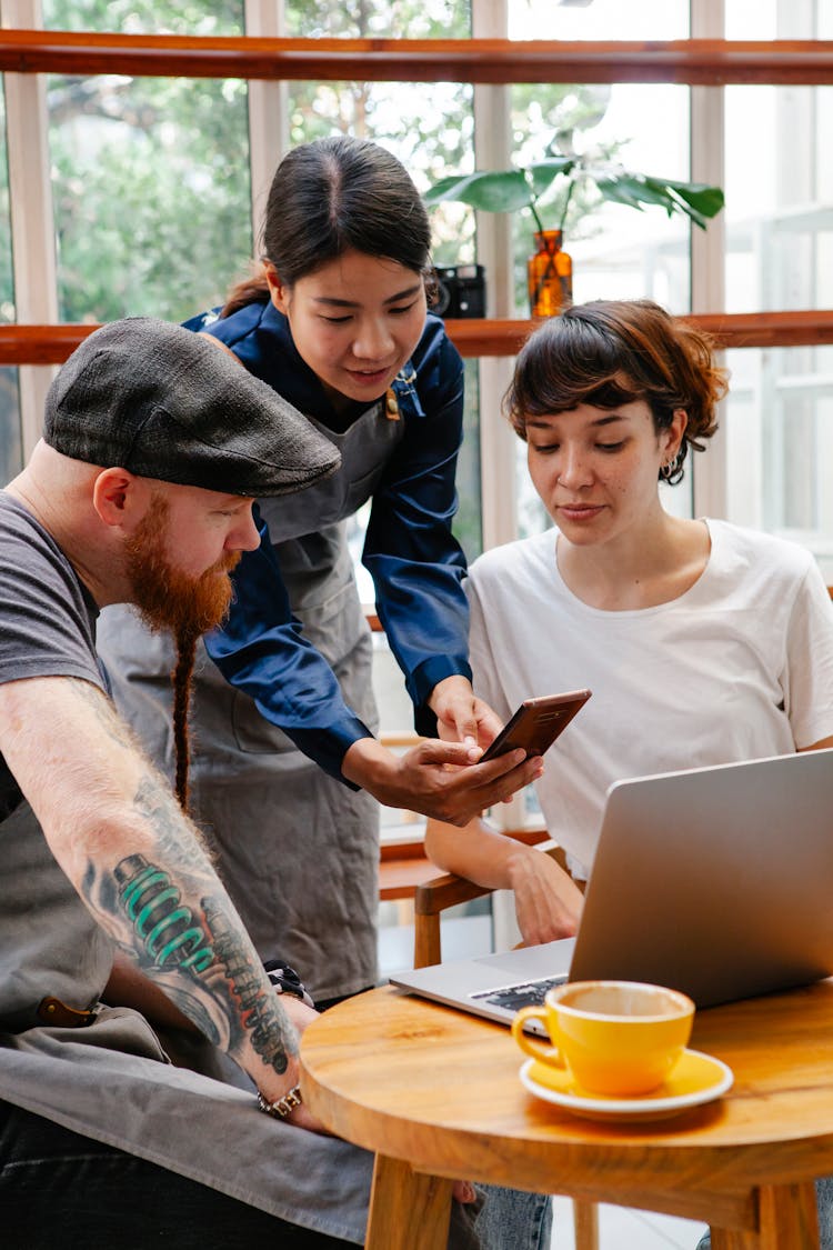 Coworkers Working On Laptop In Cafeteria