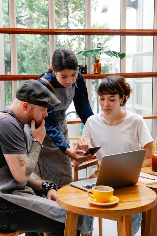 Colleagues working on laptop and phone in cafeteria