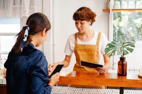 Cafe employees with tablet and smartphone speaking at counter