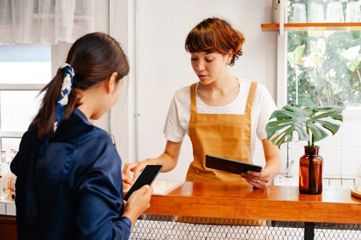 Two women engaging in discussion at a café counter with a tropical plant.