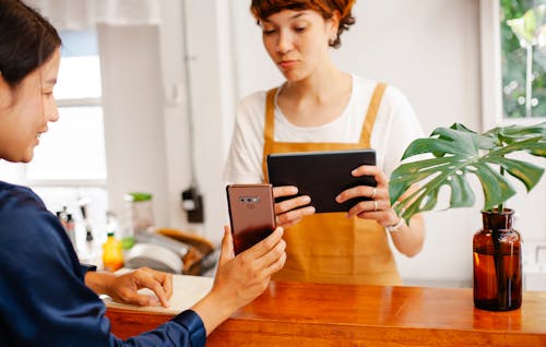 Crop multiracial cafe colleagues sharing smartphone at counter