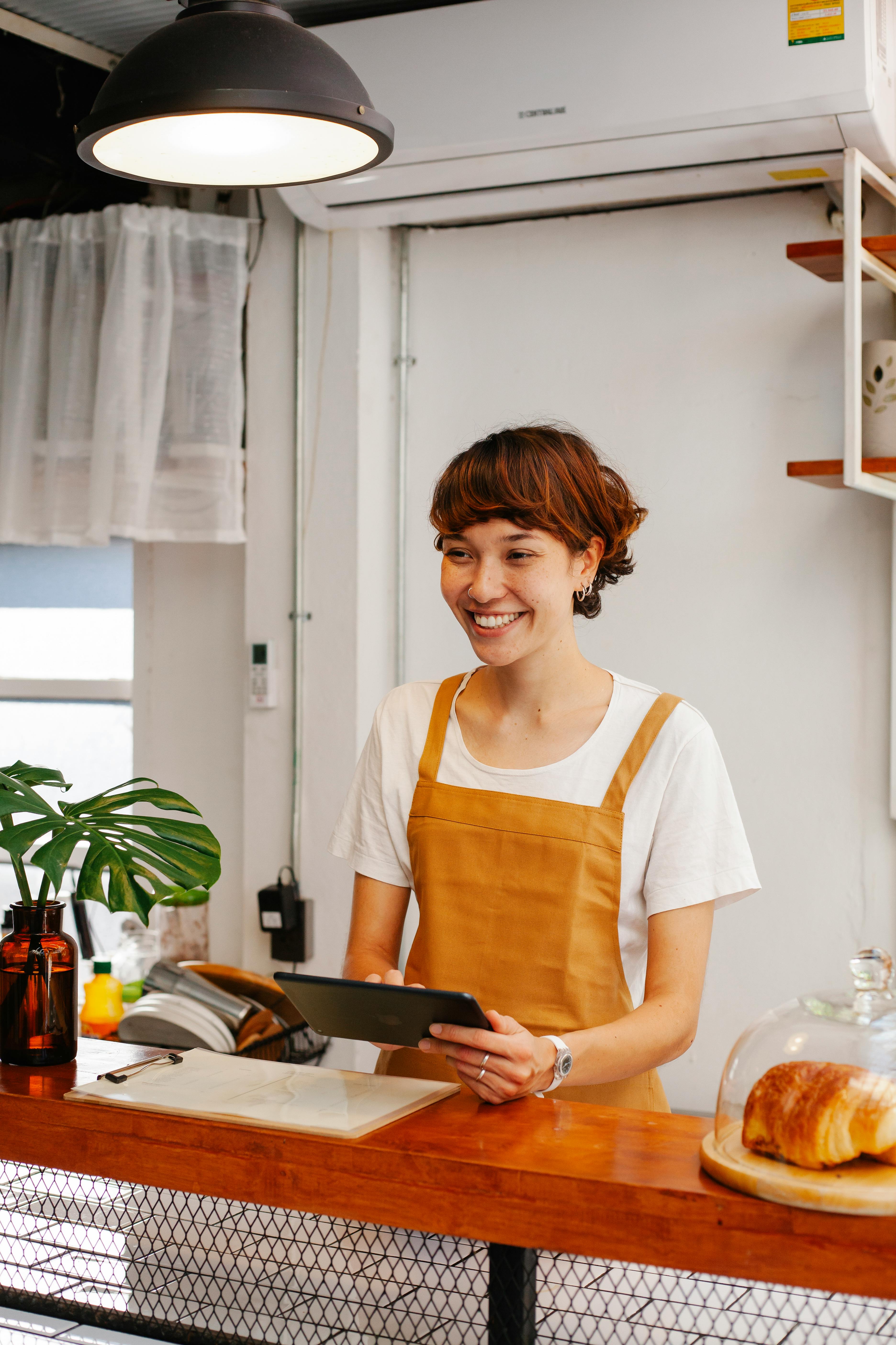 cheerful employee with tablet at counter in bakery