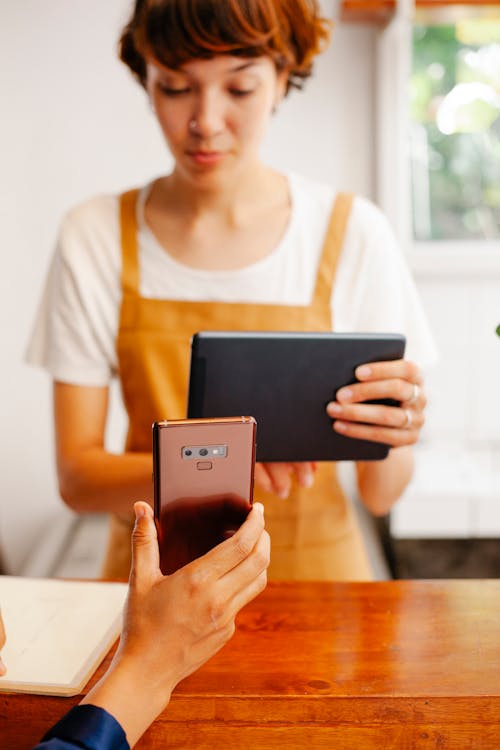 Free Crop worker with tablet against partner with smartphone in cafe Stock Photo