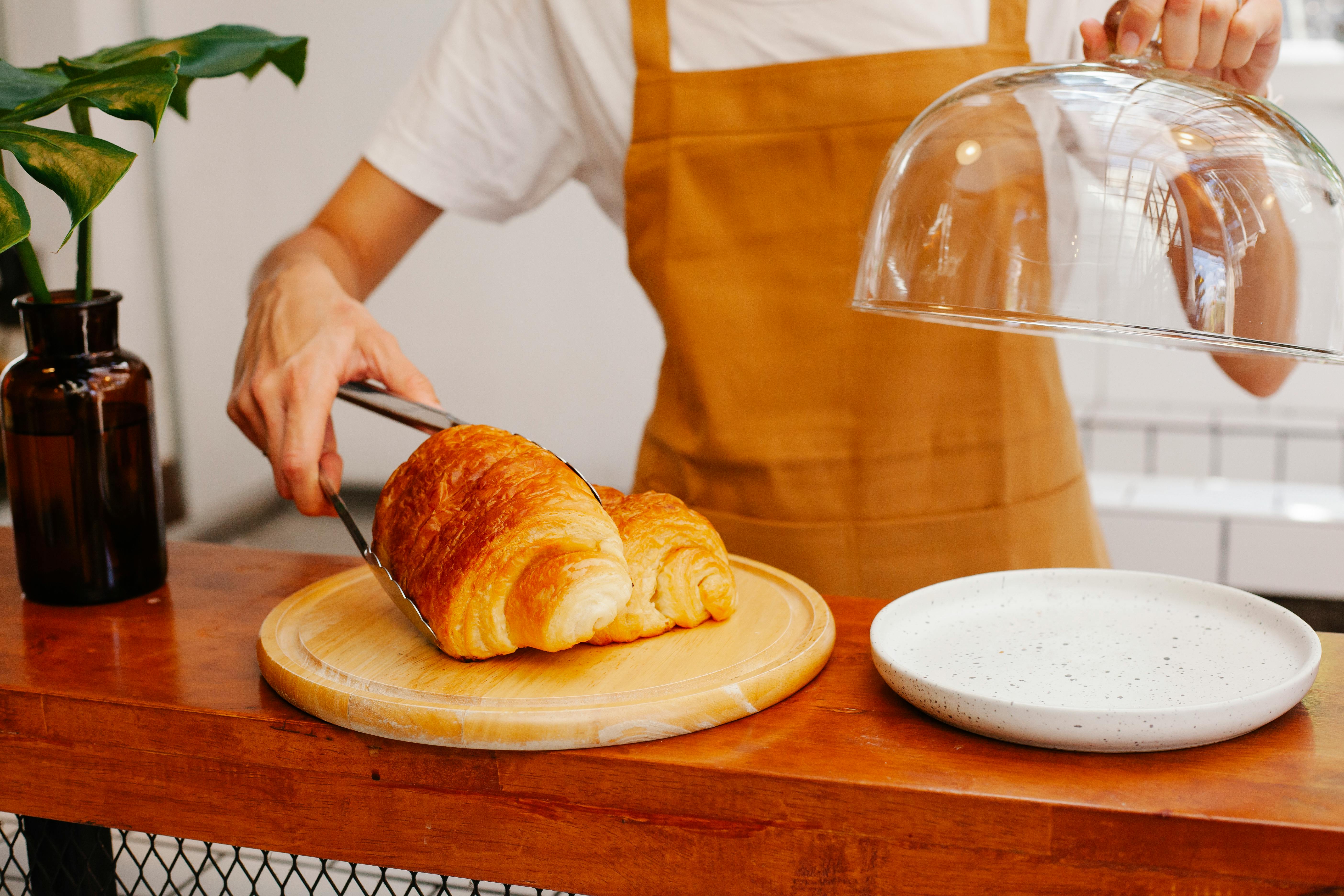 crop baker putting delicious puffs on wooden plate in cafe