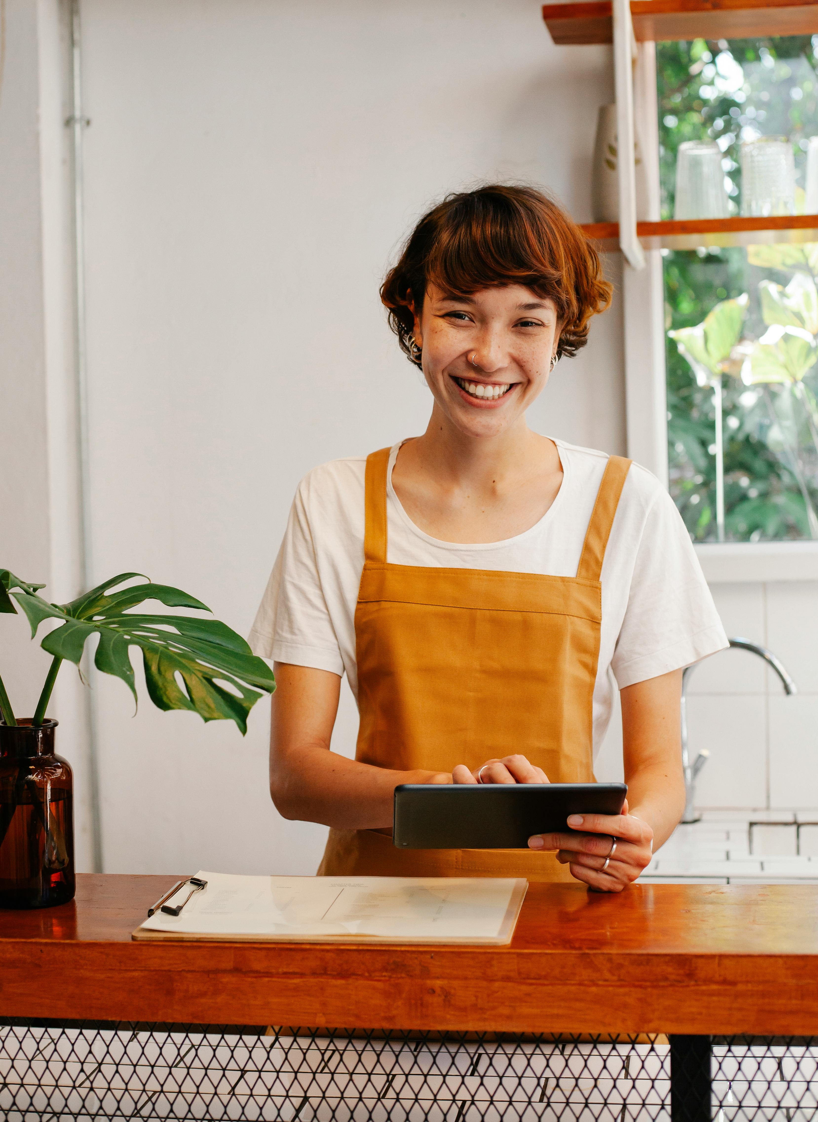 cheerful employee with tablet at cafe counter
