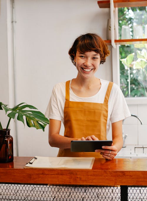 Cheerful employee with tablet at cafe counter