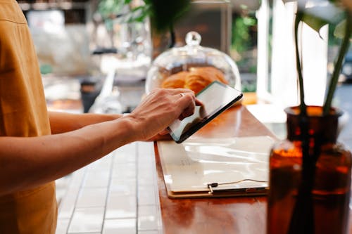 Free Crop employee touching screen on tablet at cafeteria counter Stock Photo