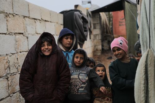 Free Group of children smiling in a Syrian refugee camp, showcasing resilience and hope. Stock Photo