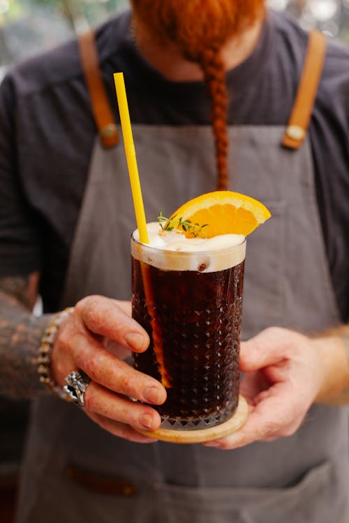 Crop barkeeper with glass of Black Velvet cocktail