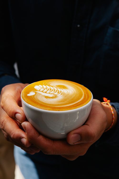 Free Crop unrecognizable male cafeteria employee with ceramic cup of tasty coffee with ornament on foam Stock Photo