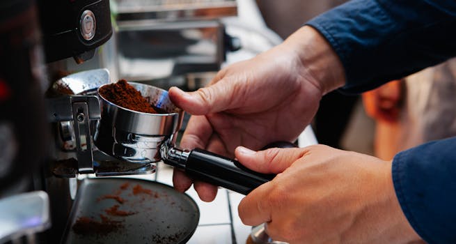 A barista is using an espresso machine to prepare coffee with freshly ground beans.