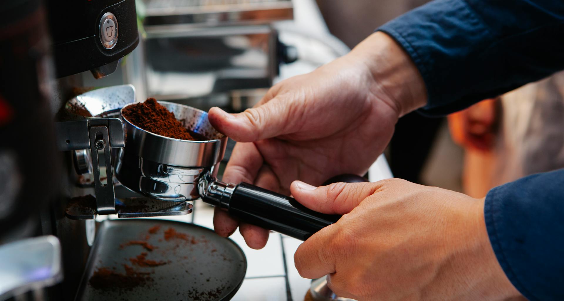 A barista is using an espresso machine to prepare coffee with freshly ground beans.