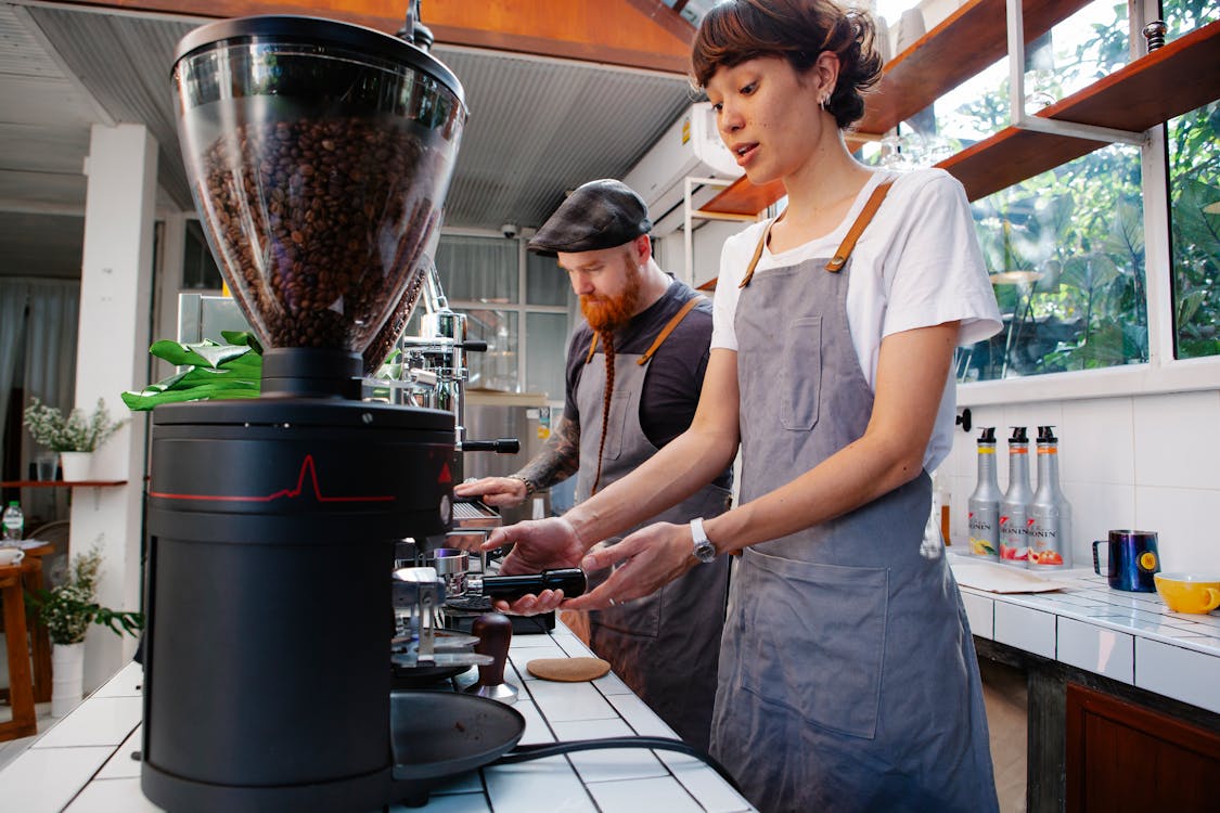 Crop baristas preparing coffee in cafe kitchen