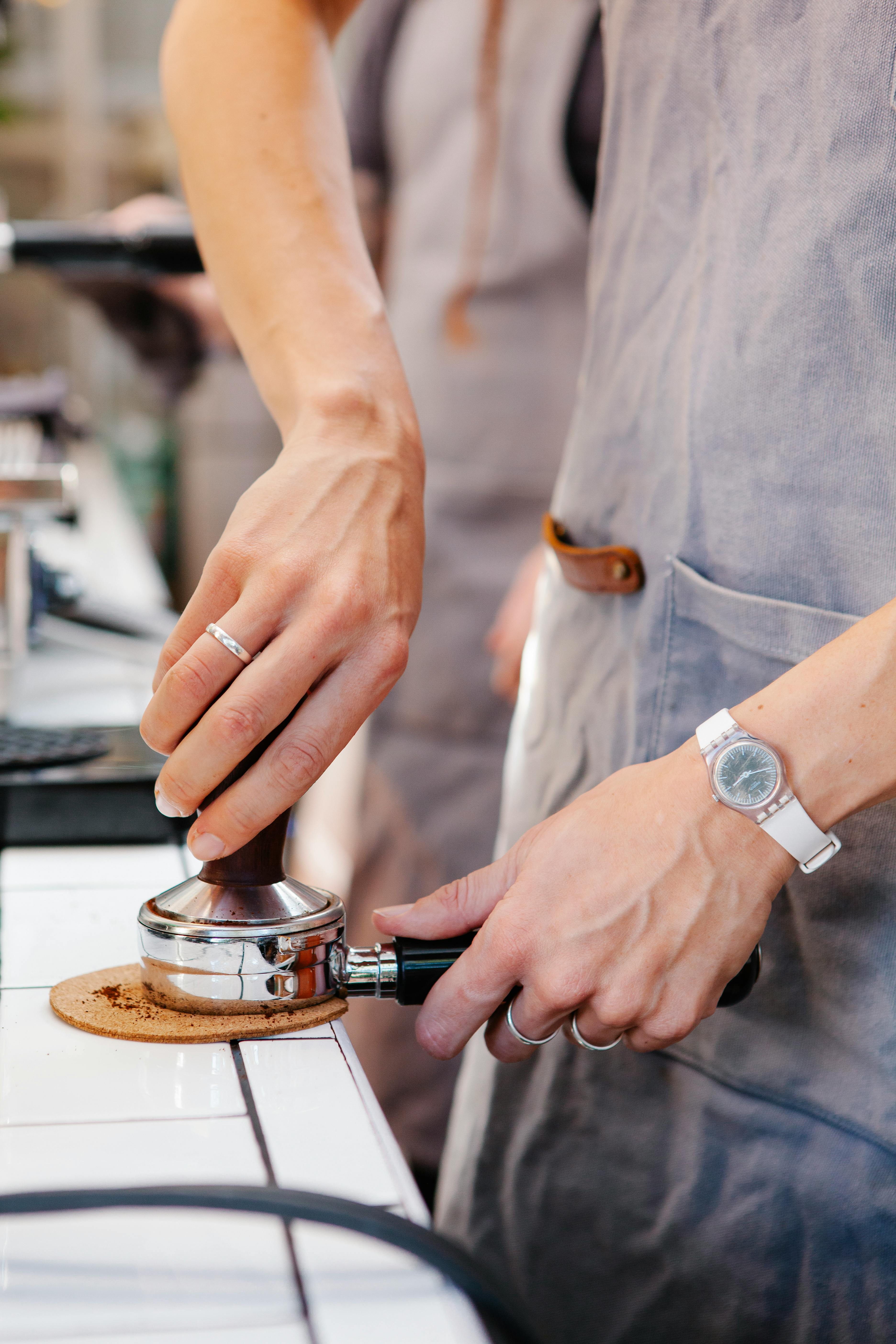 faceless barista tamping coffee in portafilter in kitchen