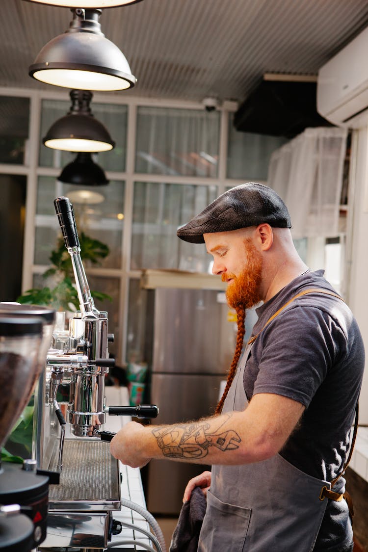 Hipster Barista Inserting Portafilter Into Coffee Machine In Kitchen