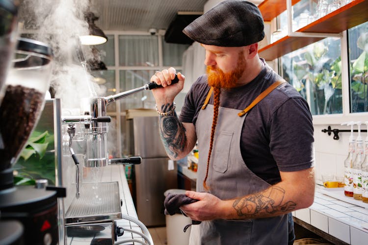 Tattooed Barista Cleaning Coffee Maker With Steam