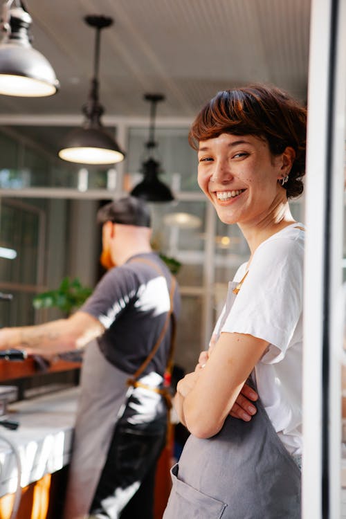 Smiling barista with unrecognizable partner in cafeteria kitchen