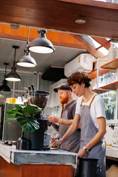 Two baristas preparing coffee drinks in a modern café with natural light.