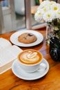 Aromatic latte served on table near book