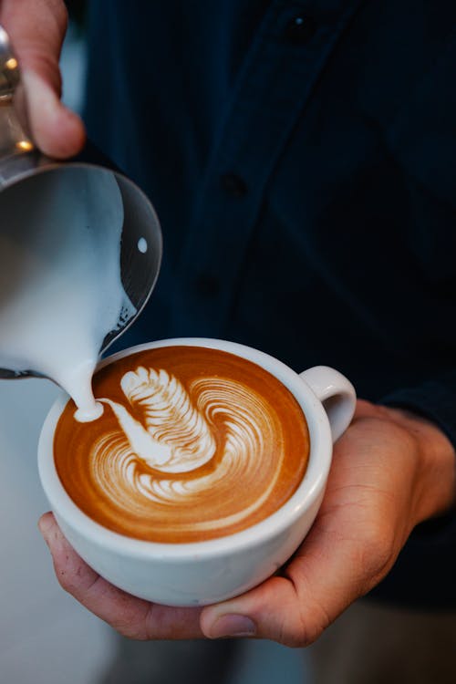 Free Crop faceless barista adding froth into cup of latte Stock Photo