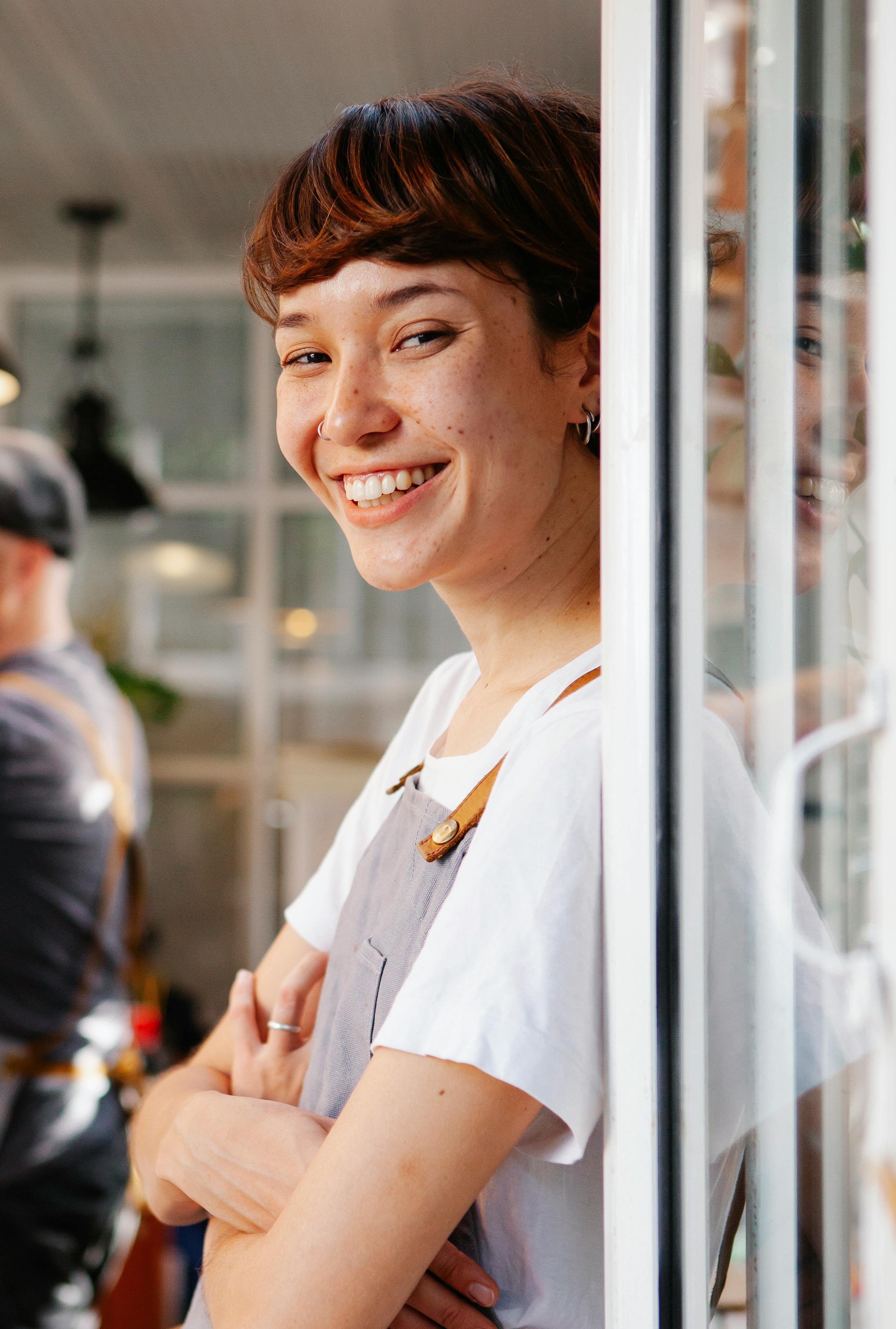 happy young woman in apron smiling at camera