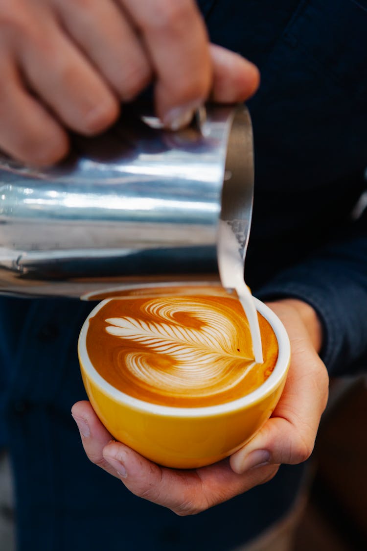 Man Pouring Cream Into Coffee With Latte Art