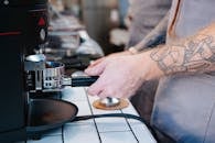 Tattooed man preparing coffee with coffee machine