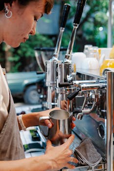 A barista steams milk in a modern café environment, showcasing professional coffee making skills.