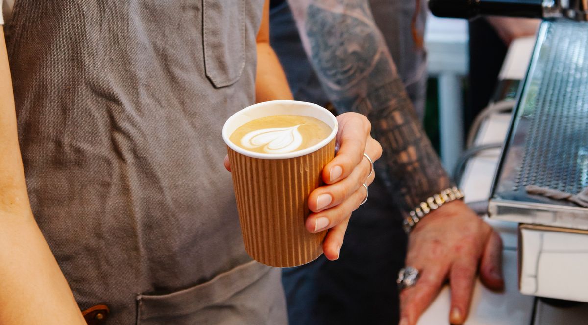 Barista handing a takeaway coffee to a customer at Grounded Coffee Co. in Fitzroy