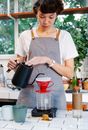 Pensive female barista pouring coffee in light kitchen